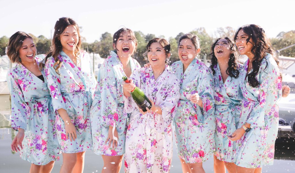 A bride bursts a champagne bottle with her bridesmaids on her wedding day.